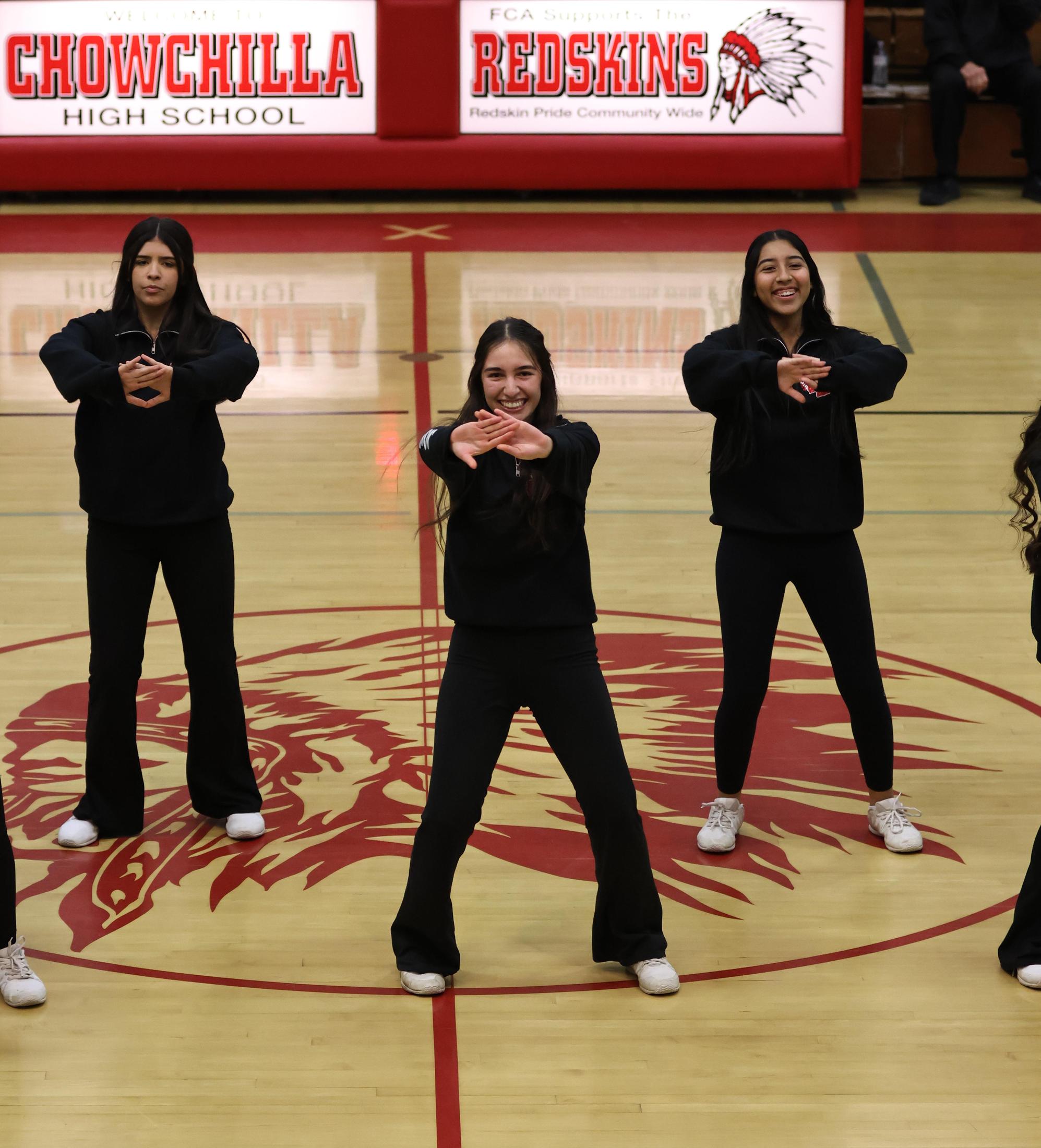Varsity girls cheering at a basketball game against Mariposa