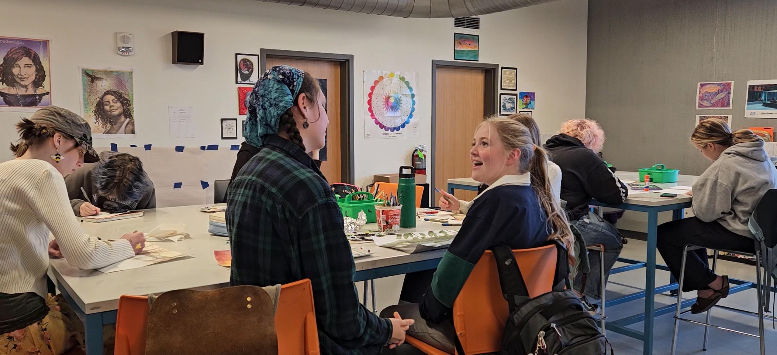 Art students chat in class while working on art projects