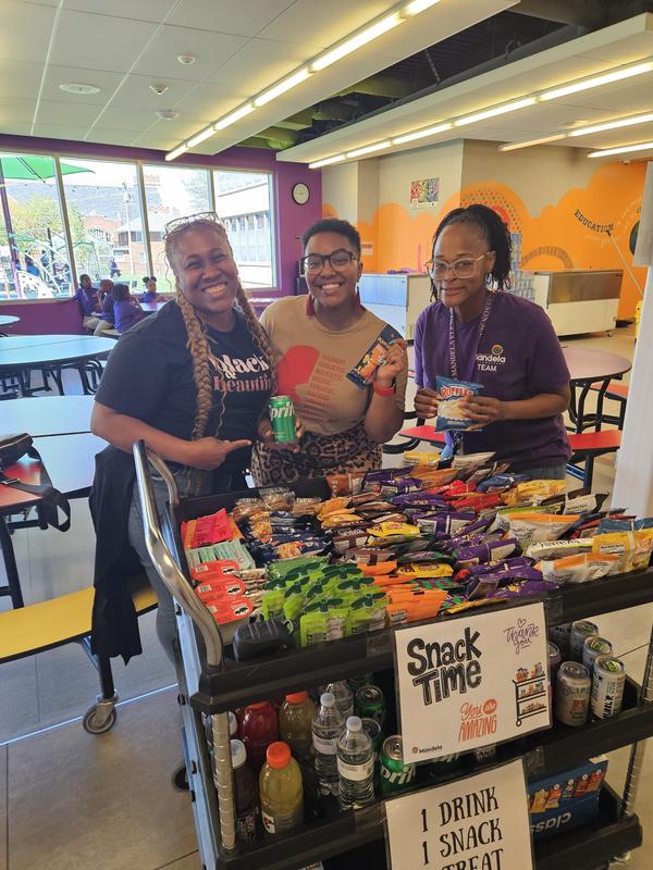 3 teachers in front of a cart full of snacks