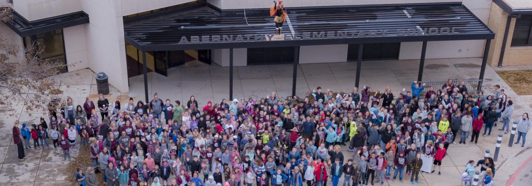 Elementary students pose with principal dressed as turkey atop the building