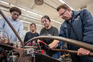 Mr. Marty Supple, Artesia High School automotive teacher, works with students during class.