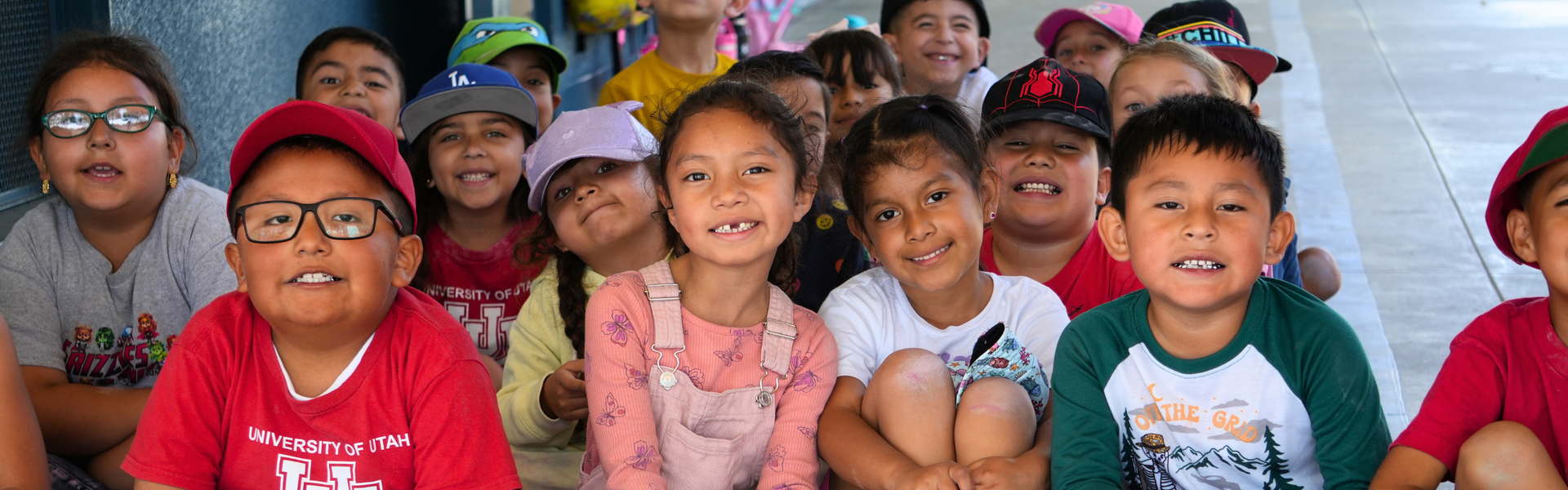 A group of children smiling while sitting together outdoors.