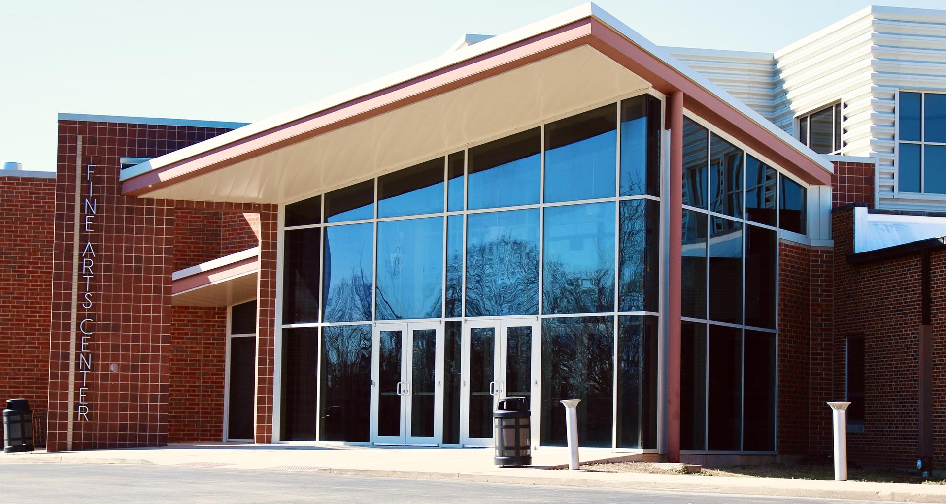 Modern architectural entrance of the Fine Arts Center with large glass doors.