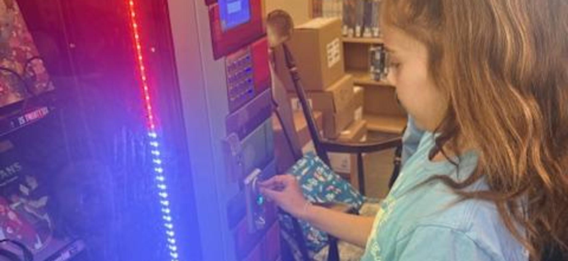 A child uses a vending machine with colorful lights in a store.