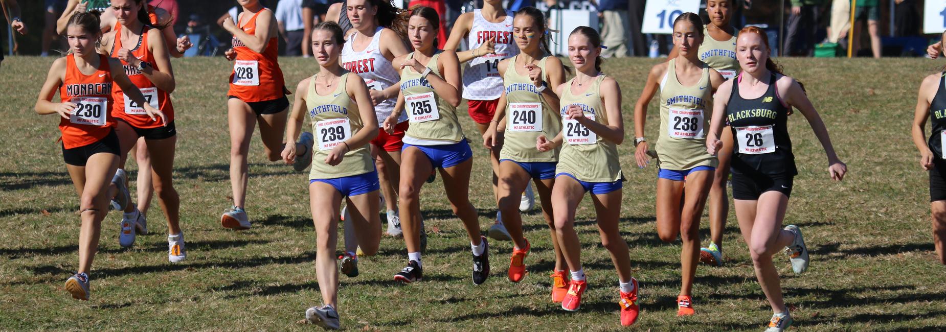 Group of female runners competing in a cross-country race on a grassy field.