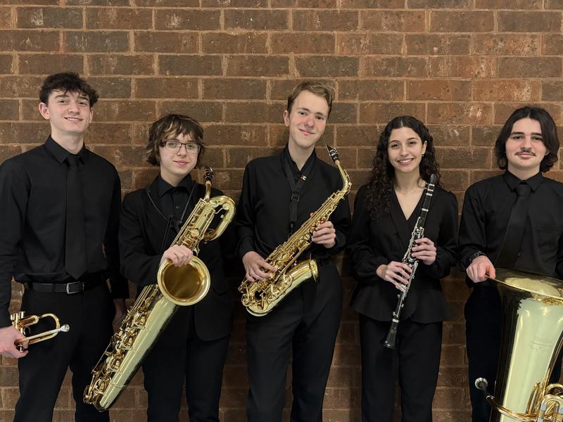 Image of 5 high school band musicians holding their saxophone and trumpet