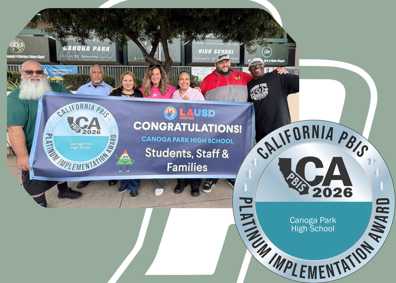 Staff poses for picture with PBIS banner
