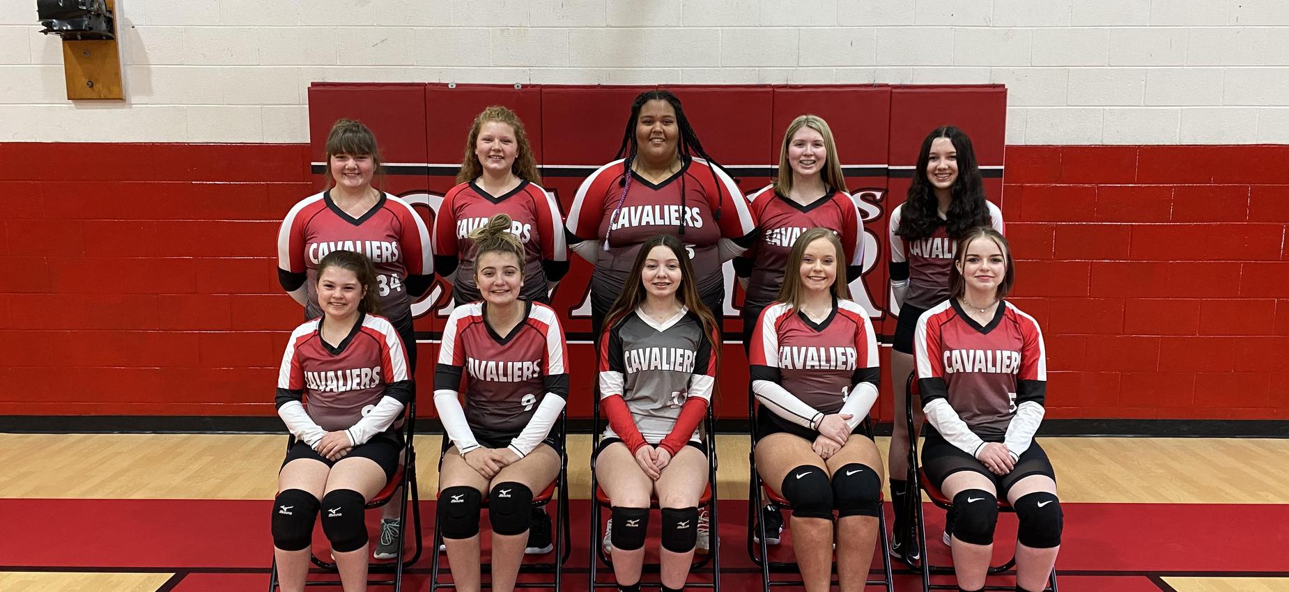 A group of volleyball players pose in a gym.