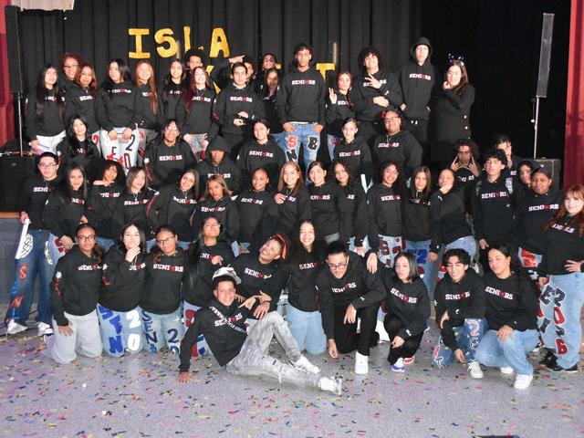 Group of students in matching hoodies posing together on a stage.