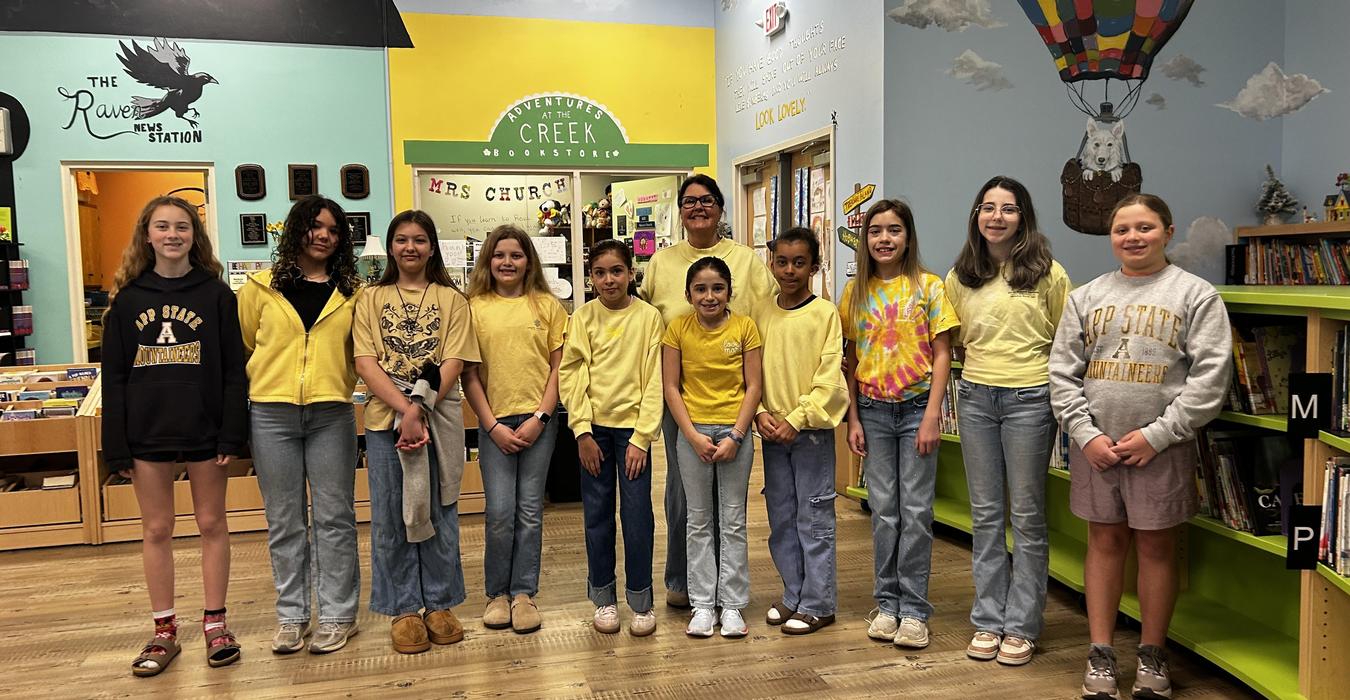 A group of girls in yellow outfits posing together in a brightly colored library.