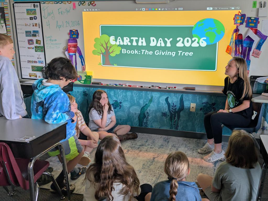 A high school student teaching elementary children about Earth Day.