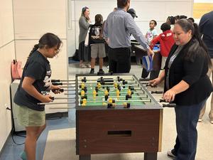 A mentor plays foosball with her student