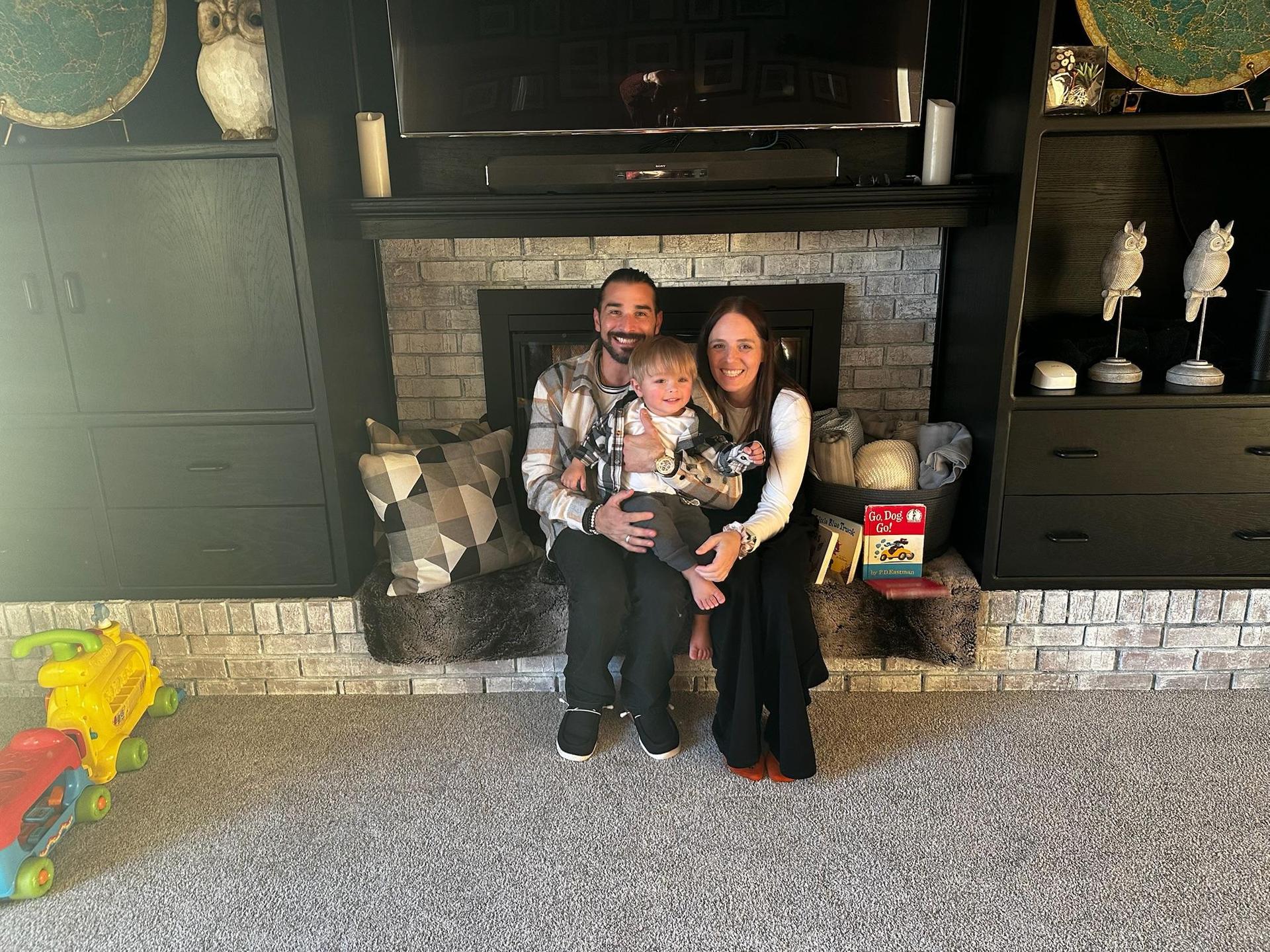 Mr. Evans sits with his wife and son by a fireplace. 