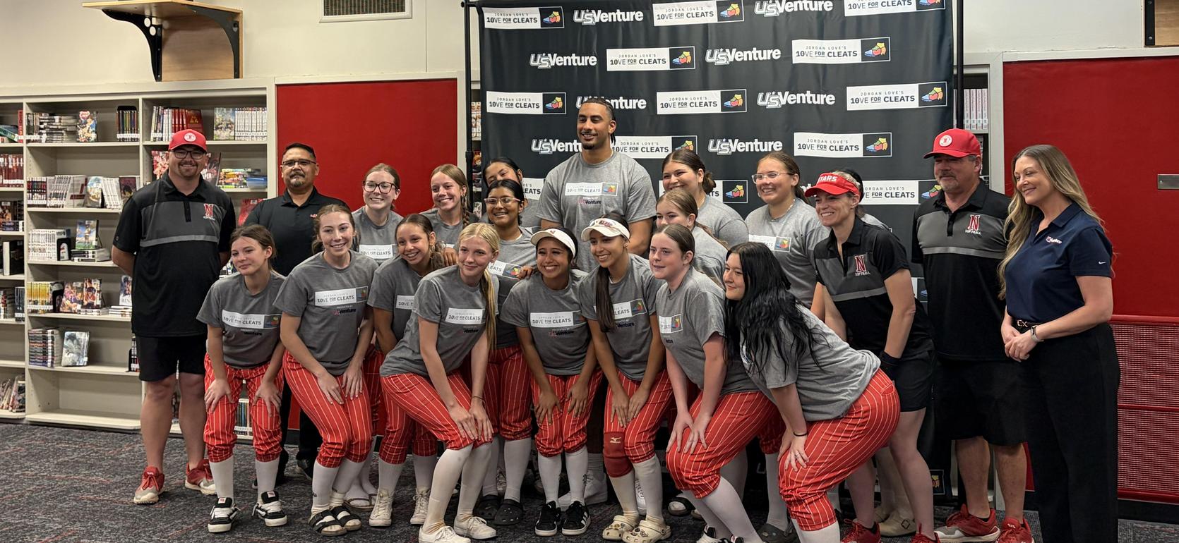 Group photo of a sports team with coaches in a gym setting.