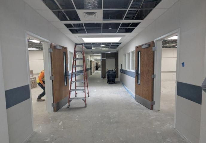 Under construction hallway with a ladder and open doorways.