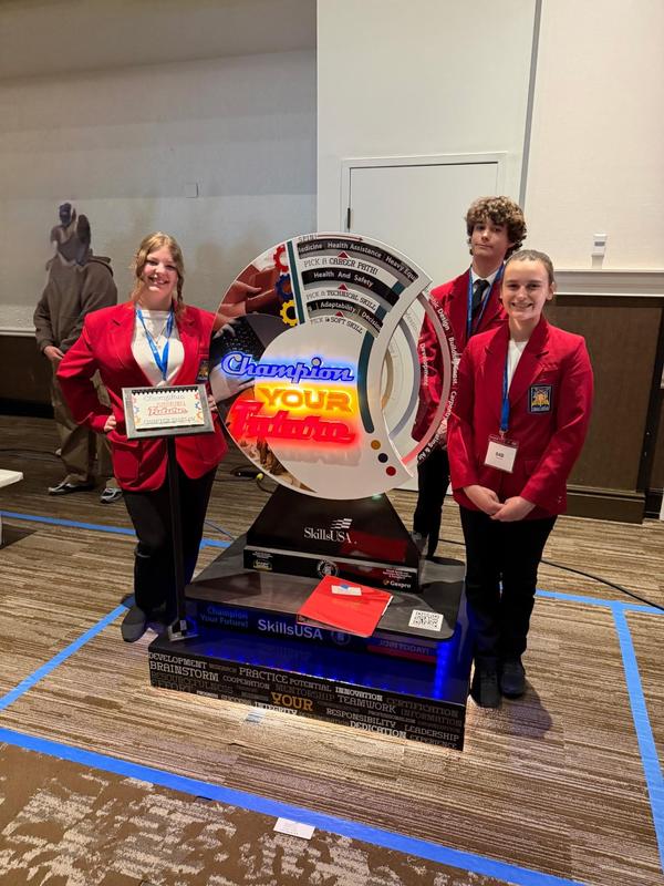 students in red jackets stand around large spinning display
