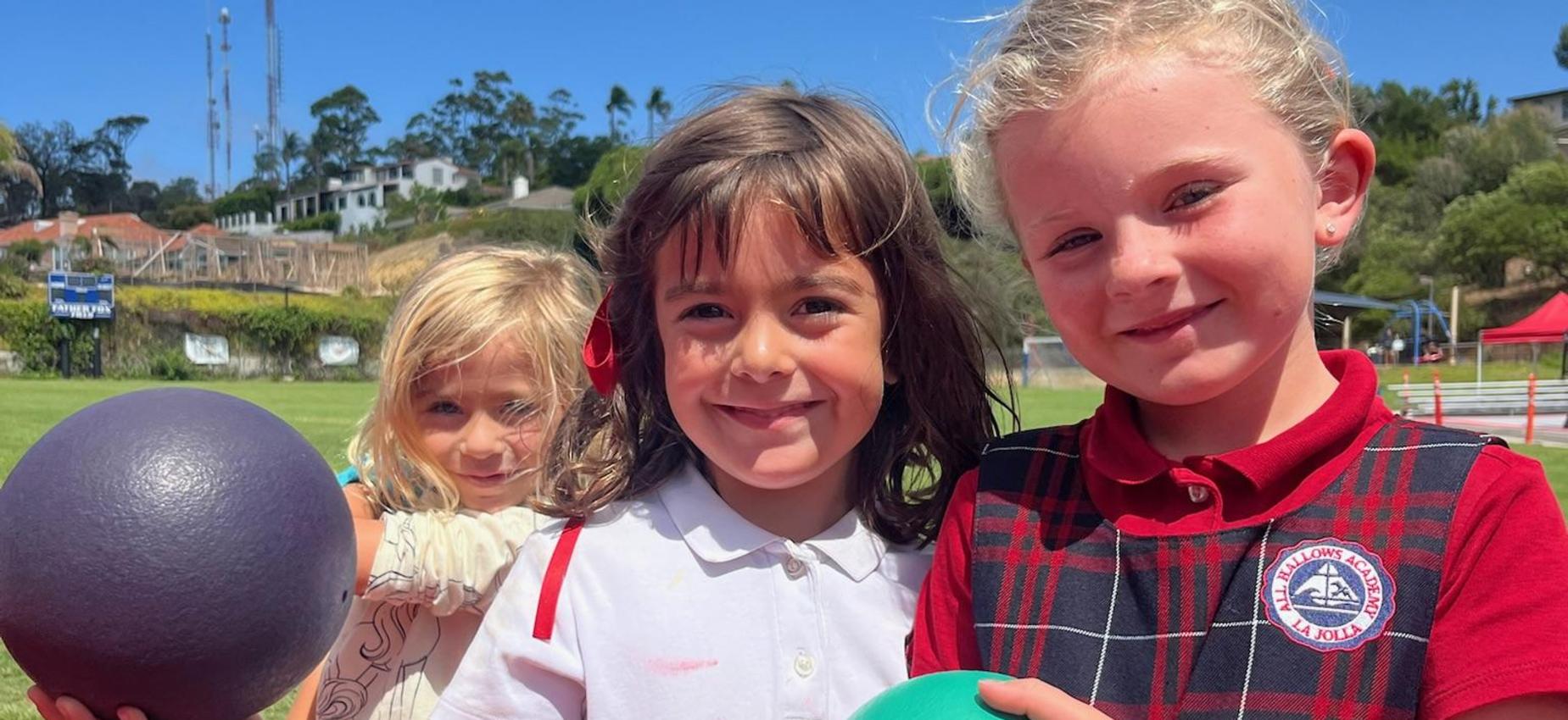 Kindergarten students posing with balls in PE class