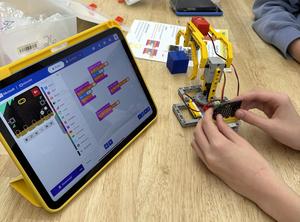 a  close-up of a tablet computer and hand holding a lego robotic arm