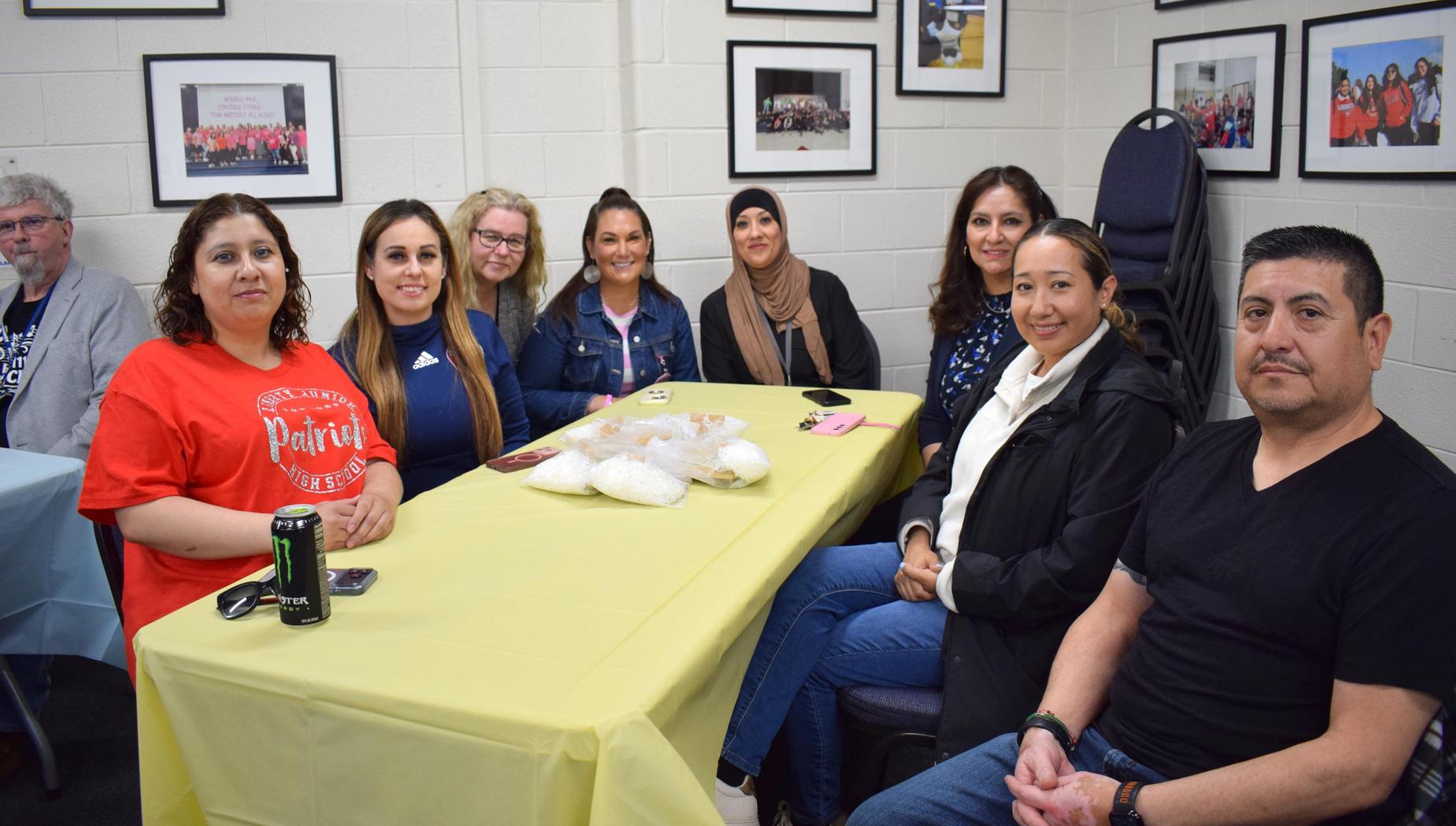 Group of nine people gathered around a table with food, smiling for the camera.