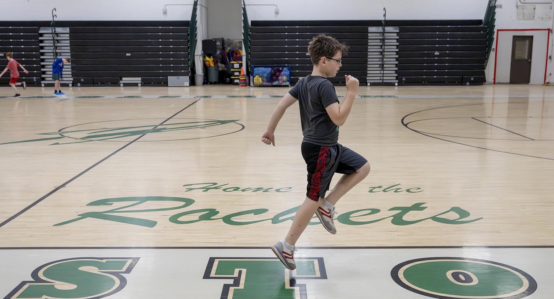 A student skips across the gym.