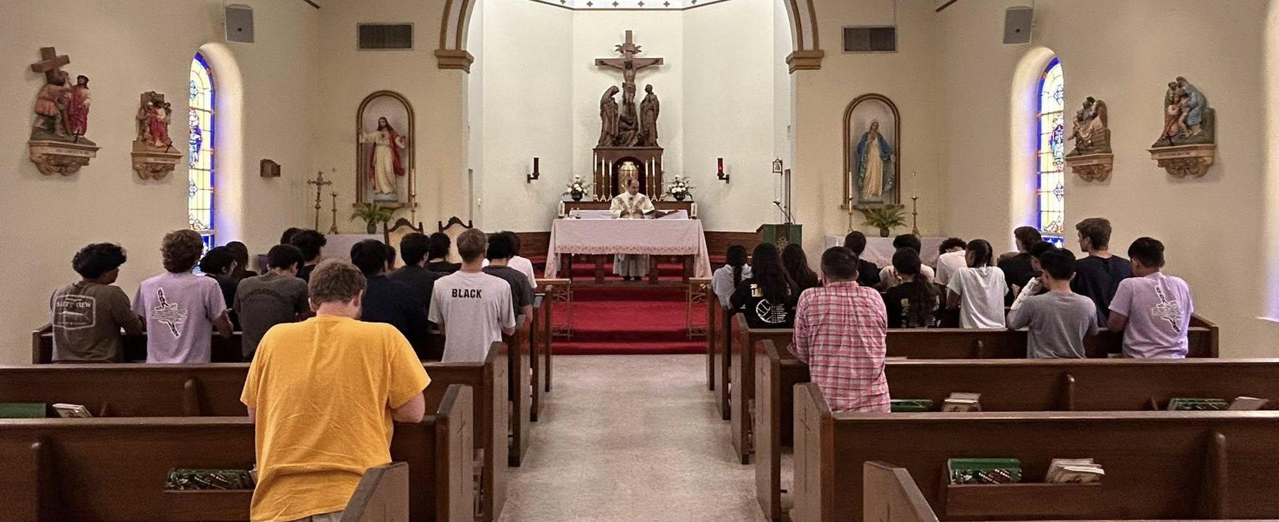 A group of people in a church attending a service with a priest at the altar.