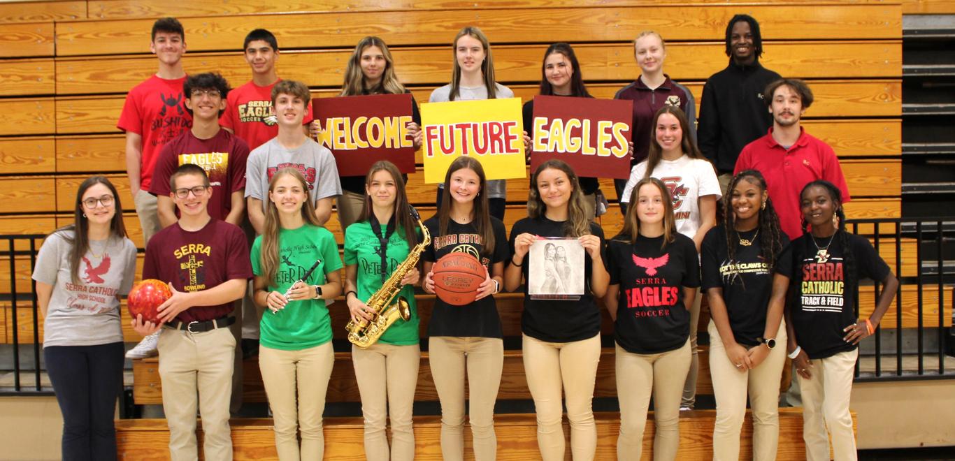 Serra Catholic students holding "Welcome Future Eagles" signs, as well as items that represent the clubs, organizations, and sports they are involved with.