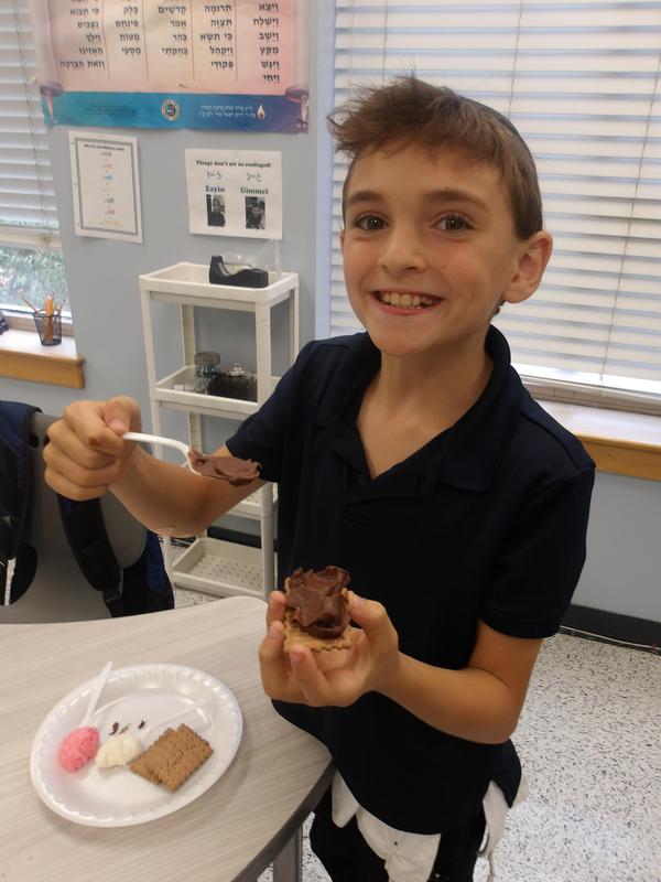 A fourth grade student spreads frosting on his shofar sandwich