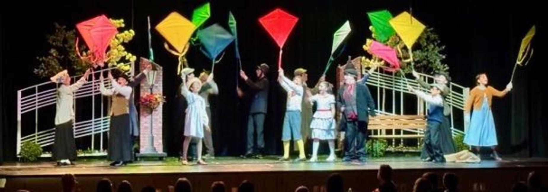 BIS musical performance with actors holding colorful kites on stage.