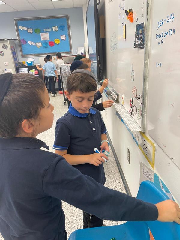 A group of third grade boys working together on a white board.