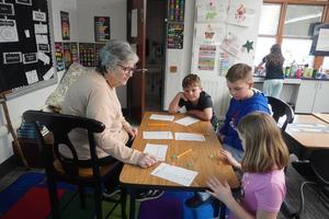 A grandmother plays Yahtzee with a group of students.