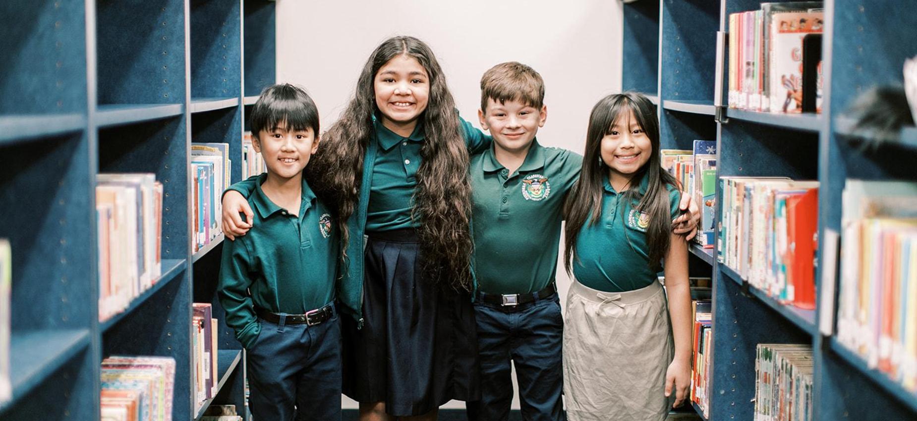 Five smiling elementary students stand together in the library
