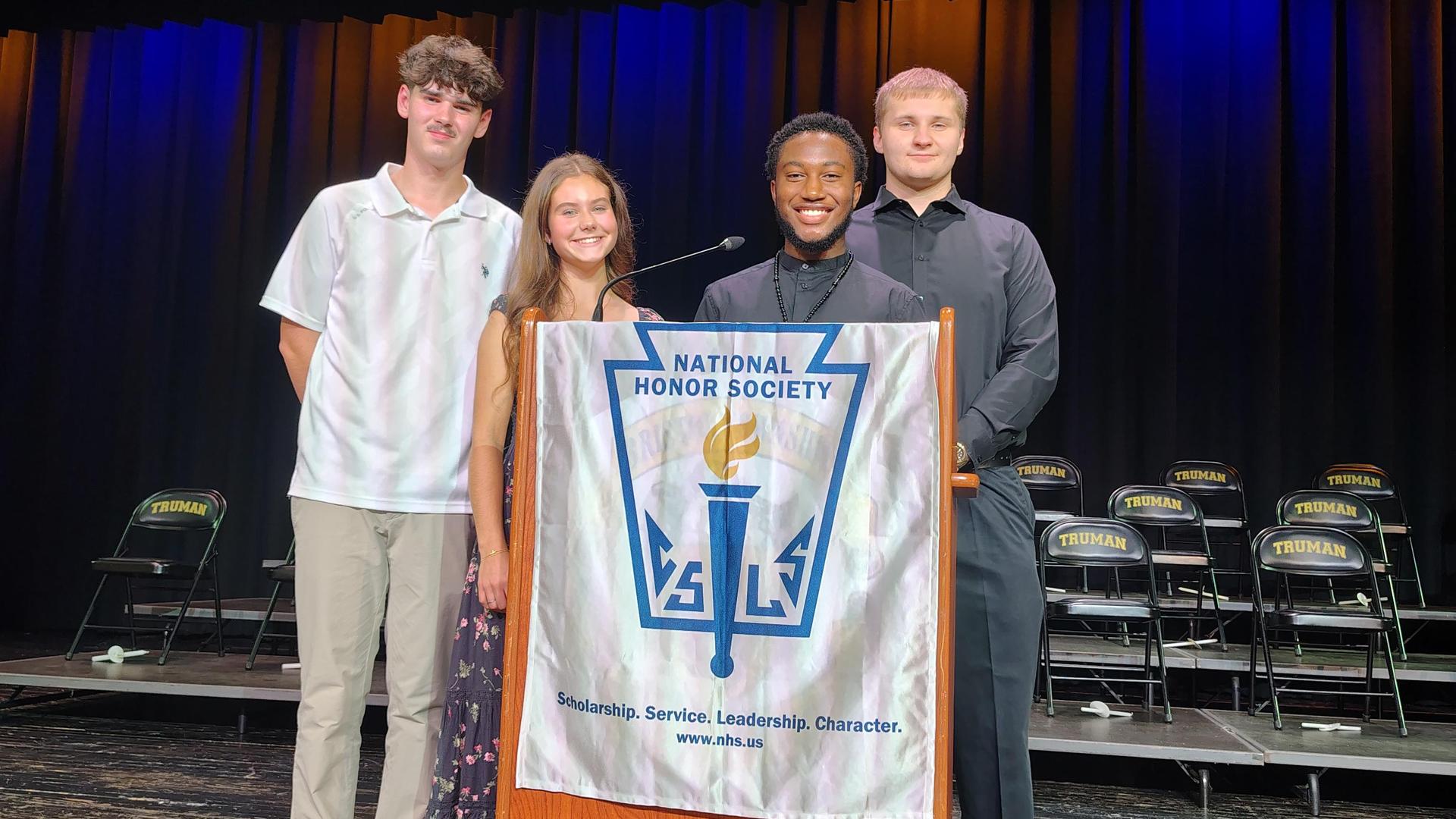 Matthew Emrich, Vice President; Nicolina Harkins, Secretary; Cory Pressley, President; and Joseph O'Neill, Treasurer stand in front of the NHS podium.