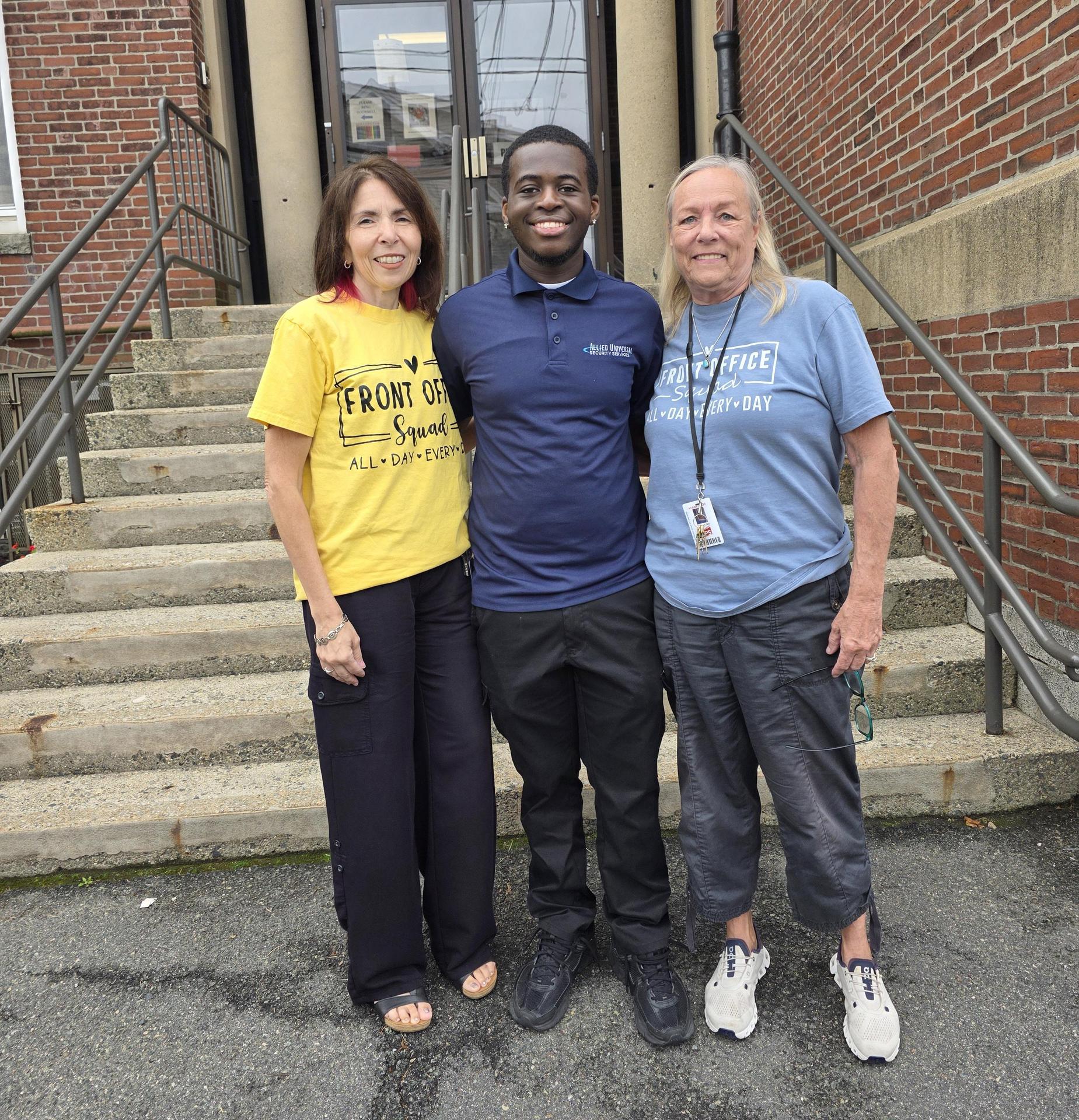 Three people standing in front of a school