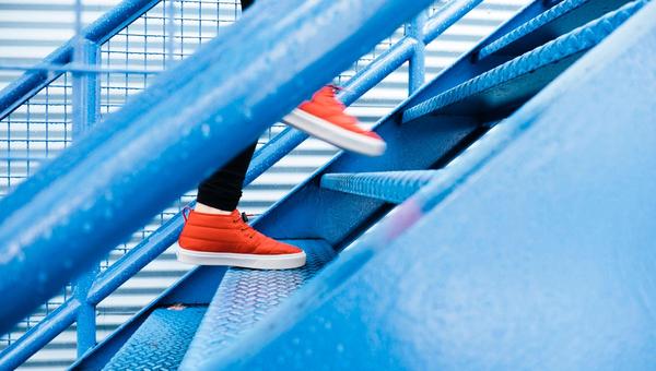 Person ascending blue stairs in red shoes.