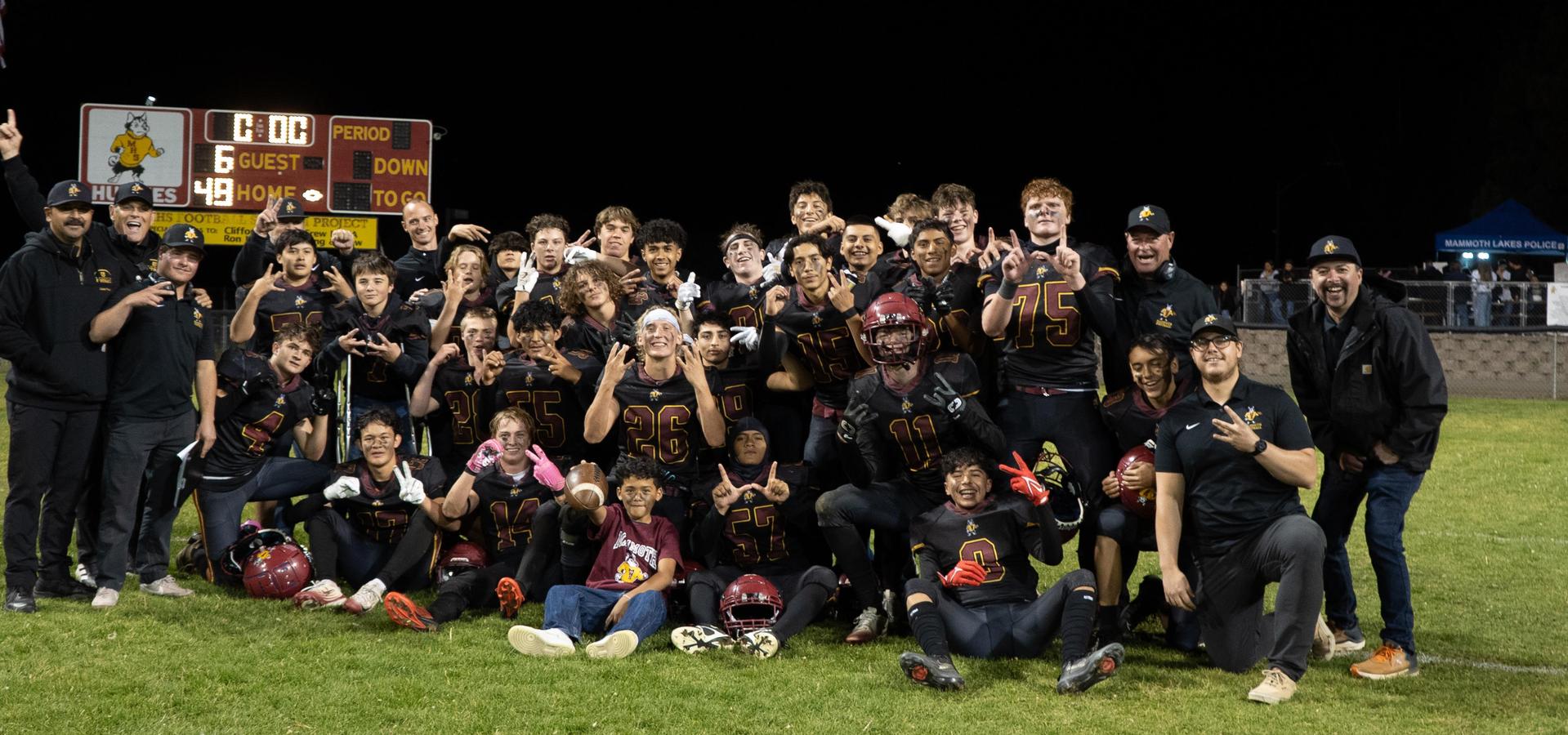 A group of football players celebrating on the field after a game.