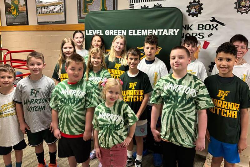 15 students who earned the Gotcha award stand in a group wearing their new shirts
