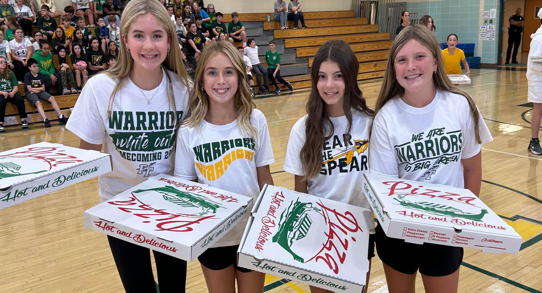 Trafford Middle School students hold pizza boxes they won during the 2025 Homecoming pep-rally