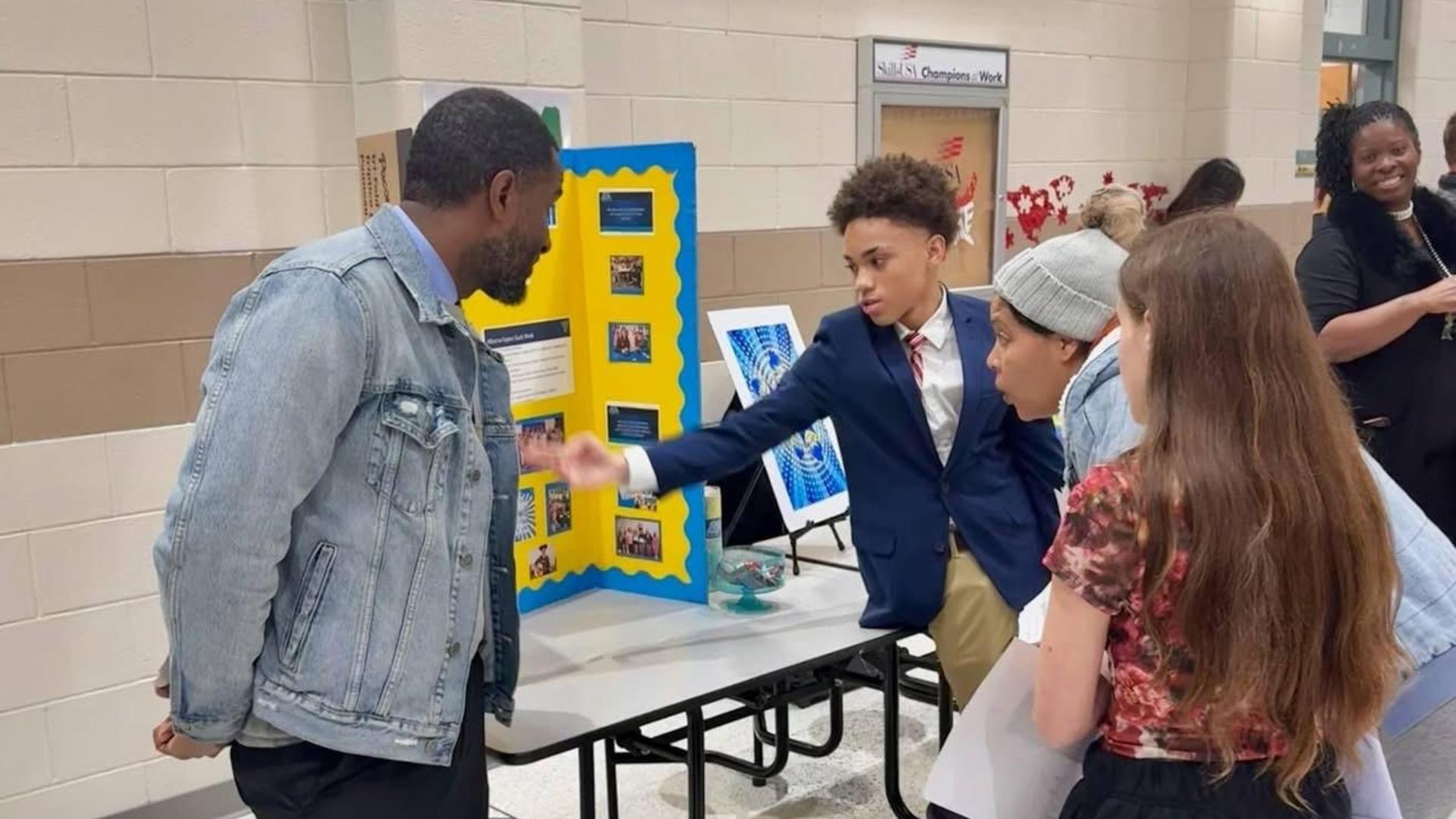 Group of students presenting a project to a visitor in a school setting.