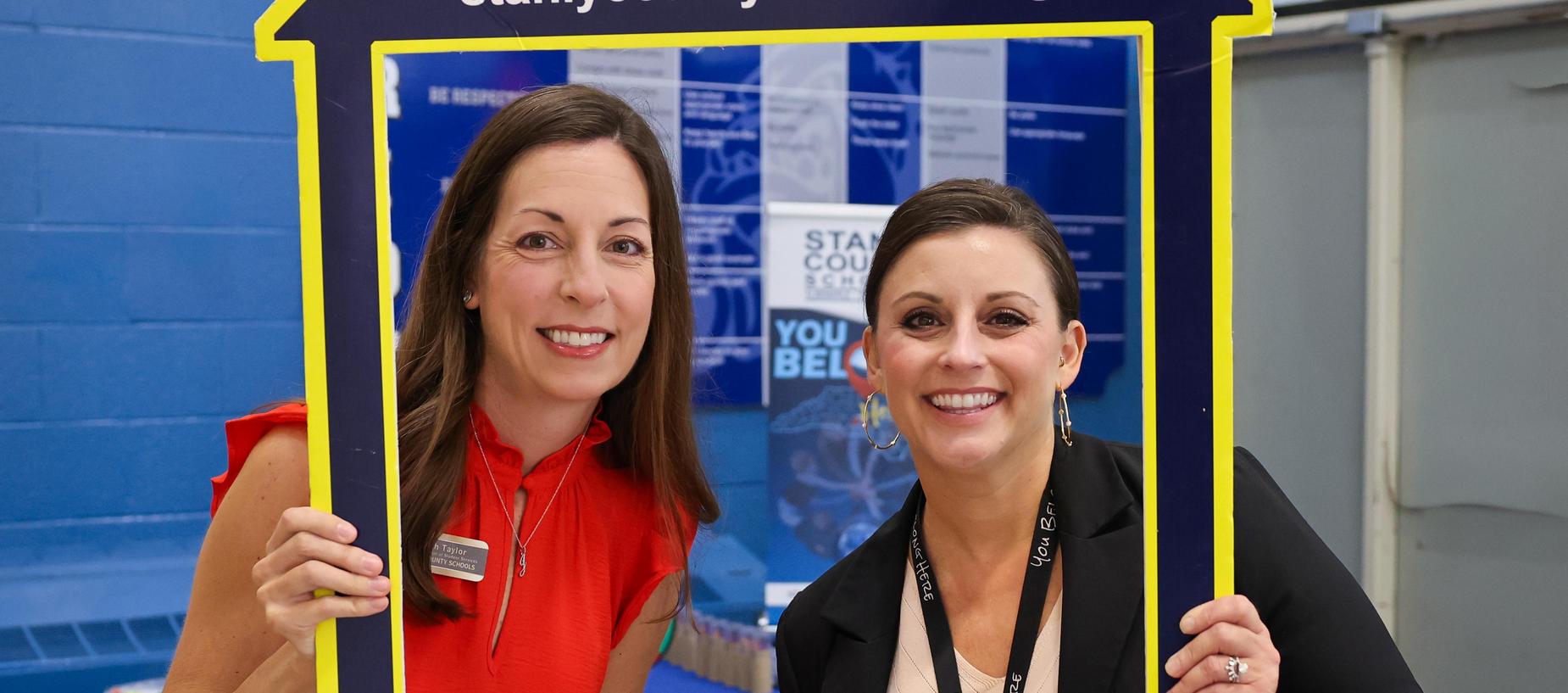 Two women smiling inside a house-shaped frame with a website link.