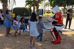 Wild Wing playing on a seesaw with children.