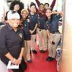 A group of smiling individuals posing together in a brightly lit hallway.
