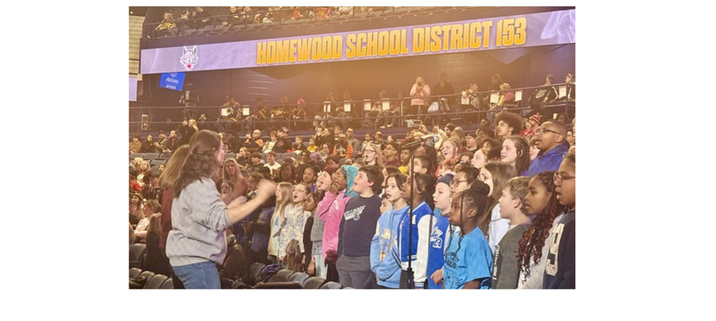teacher conducts choir of students in arena grandstand