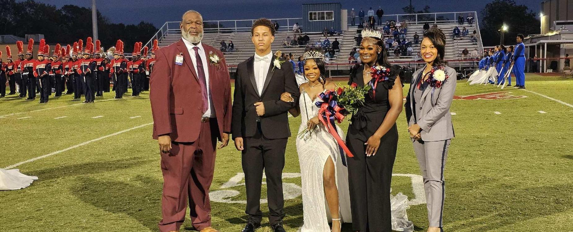 A group of four people standing on a football field during an event.