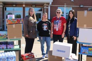 four women standing behind boxes of food donated