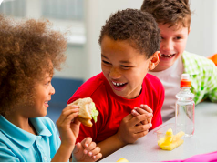 Different kids talking at at lunch table in school.
