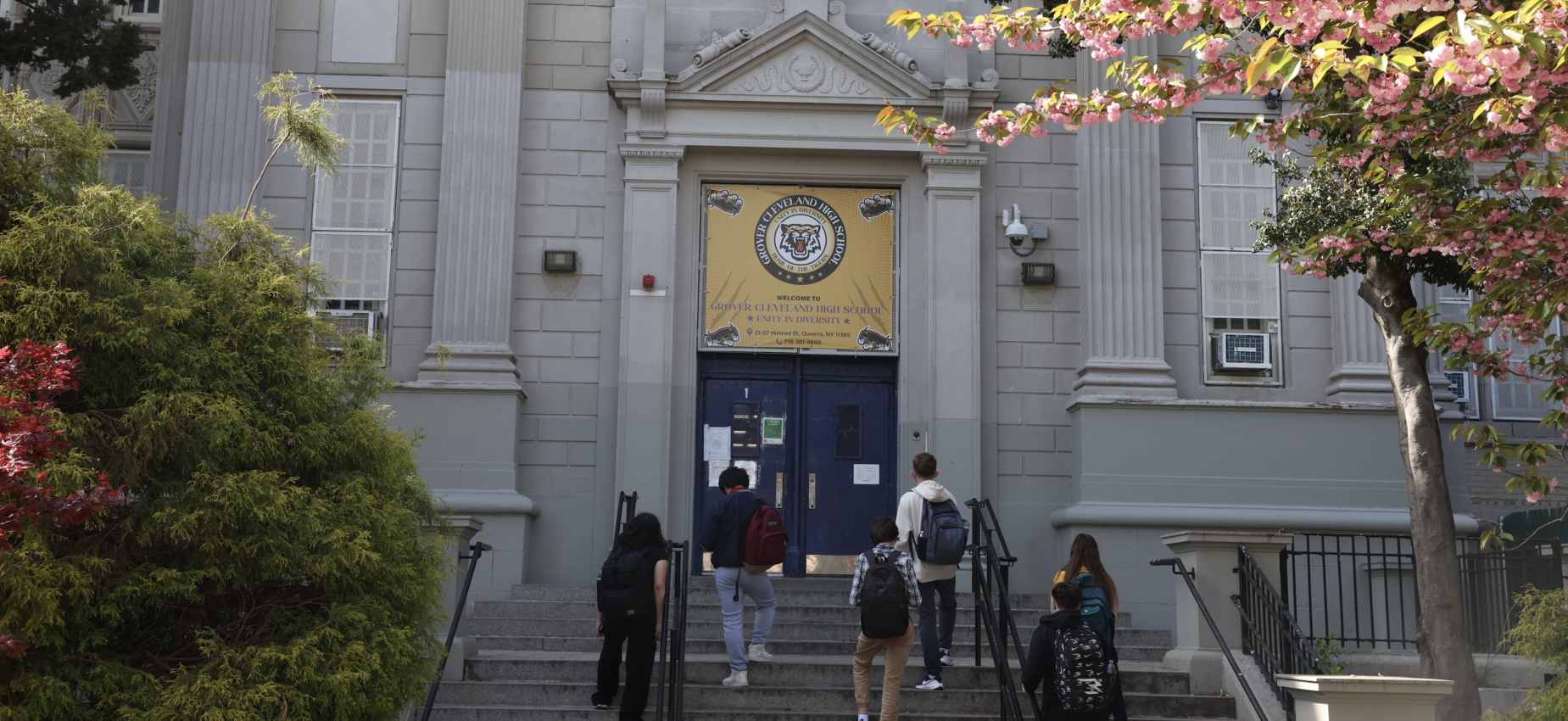 Students walking towards the entrance of a school building with decorative flowers.
