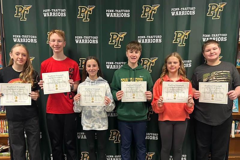 Trafford Triumphs honorees stand with their certificates in front of a Penn-Trafford backdrop