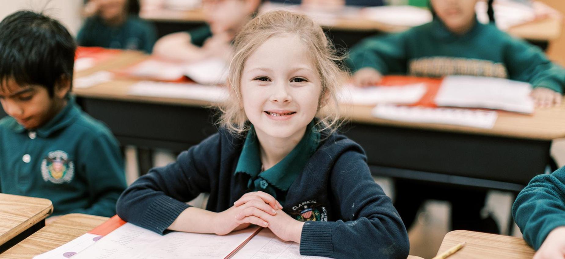 Smiling elementary student reads at her desk