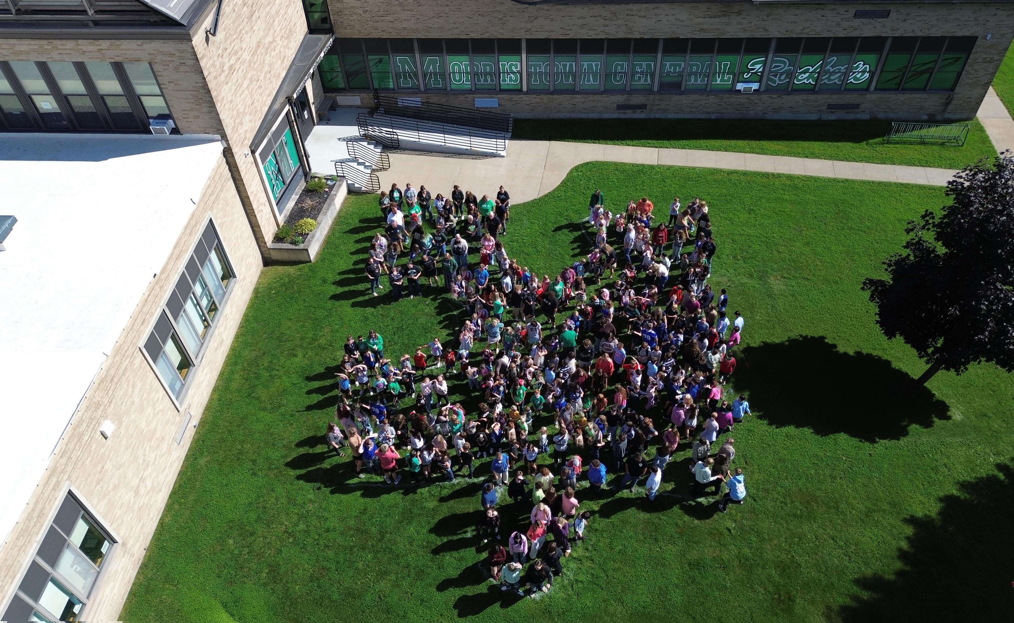 MCS students stand in a puzzle piece formation in the grass.
