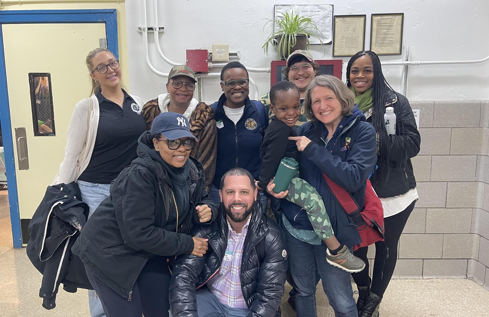 A group of people, including adults and children, pose together indoors.